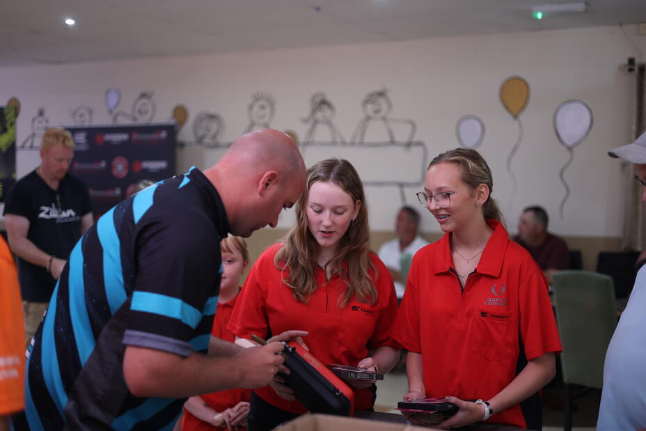Rob Cross signing a Takoma Wallet for the next generation of youth darts players