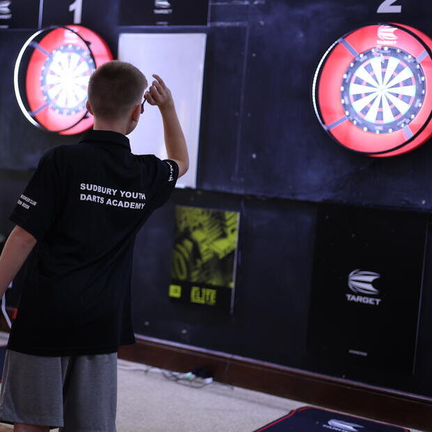 Sudbury Youth Darts Academy player throwing darts at a dartboard